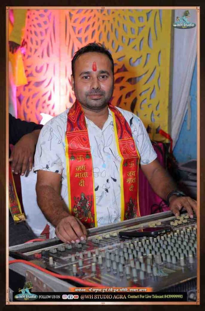 Man at Taj Kala Group event with traditional red scarf and sound mixer.